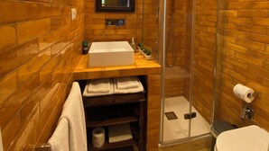 A bathroom with a wooden wall design, a glass shower enclosure, a white sink, and a toilet.
