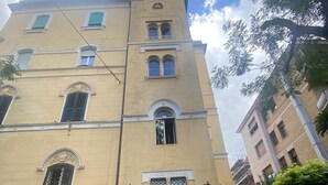 A multi-story building with a central entrance, multiple windows, and a balcony.