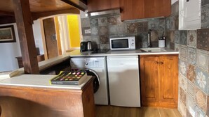 A kitchen with wooden beams, a microwave, a washing machine, and a coffee maker.