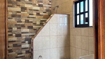 Ein Badezimmer mit gefliestem Duschbereich, Toilette und Waschbecken.
