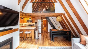 A modern loft with exposed wooden beams, a kitchen with stainless steel appliances, a dining area, and a cozy seating space. - A-Frame Cabin with Private Sauna & Hot Tub (Breckenridge)