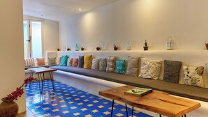 A modern living room with a sofa, patterned cushions, a wooden coffee table, and a blue patterned floor. - Aaki Hotel (León)