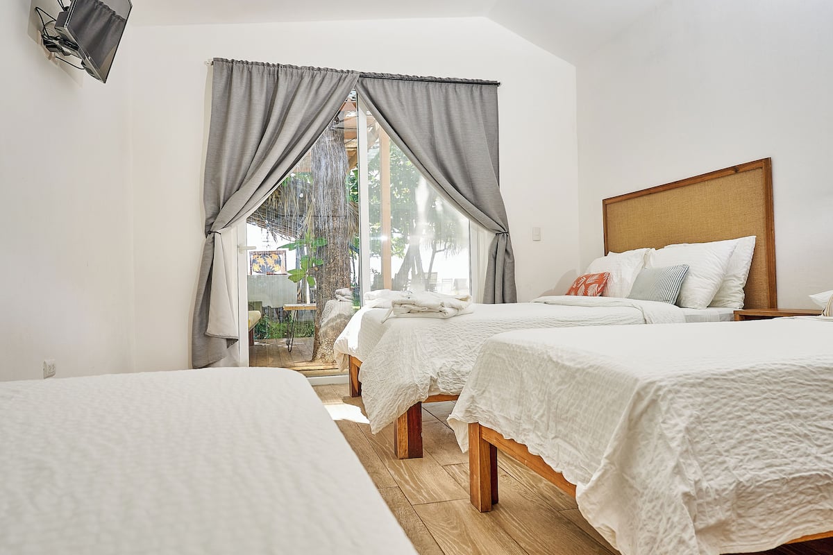 A hotel room with two beds, a wooden headboard, and a view of the outdoors.