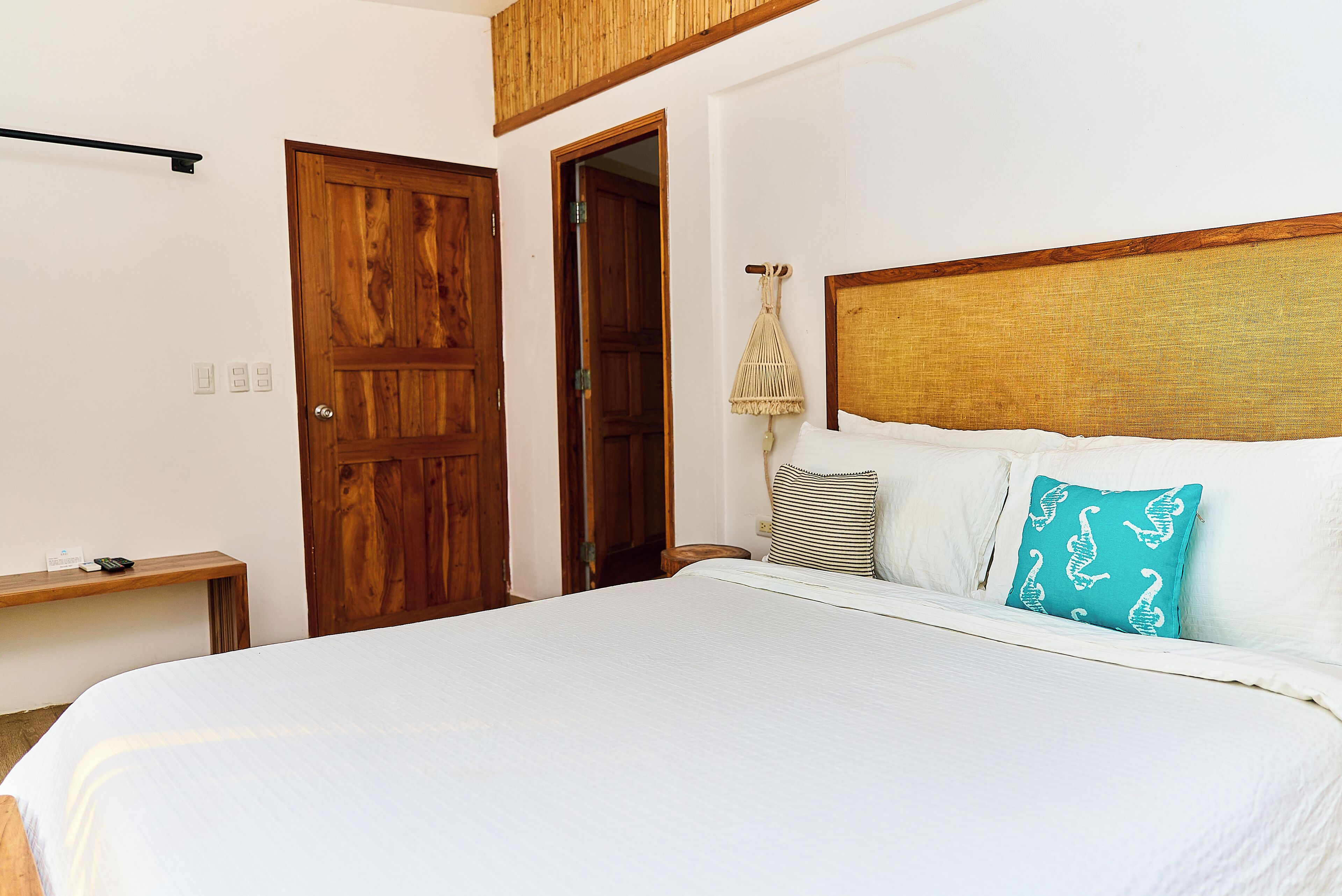 A bedroom with a large bed, wooden doors, a bedside table, and a hanging lamp.