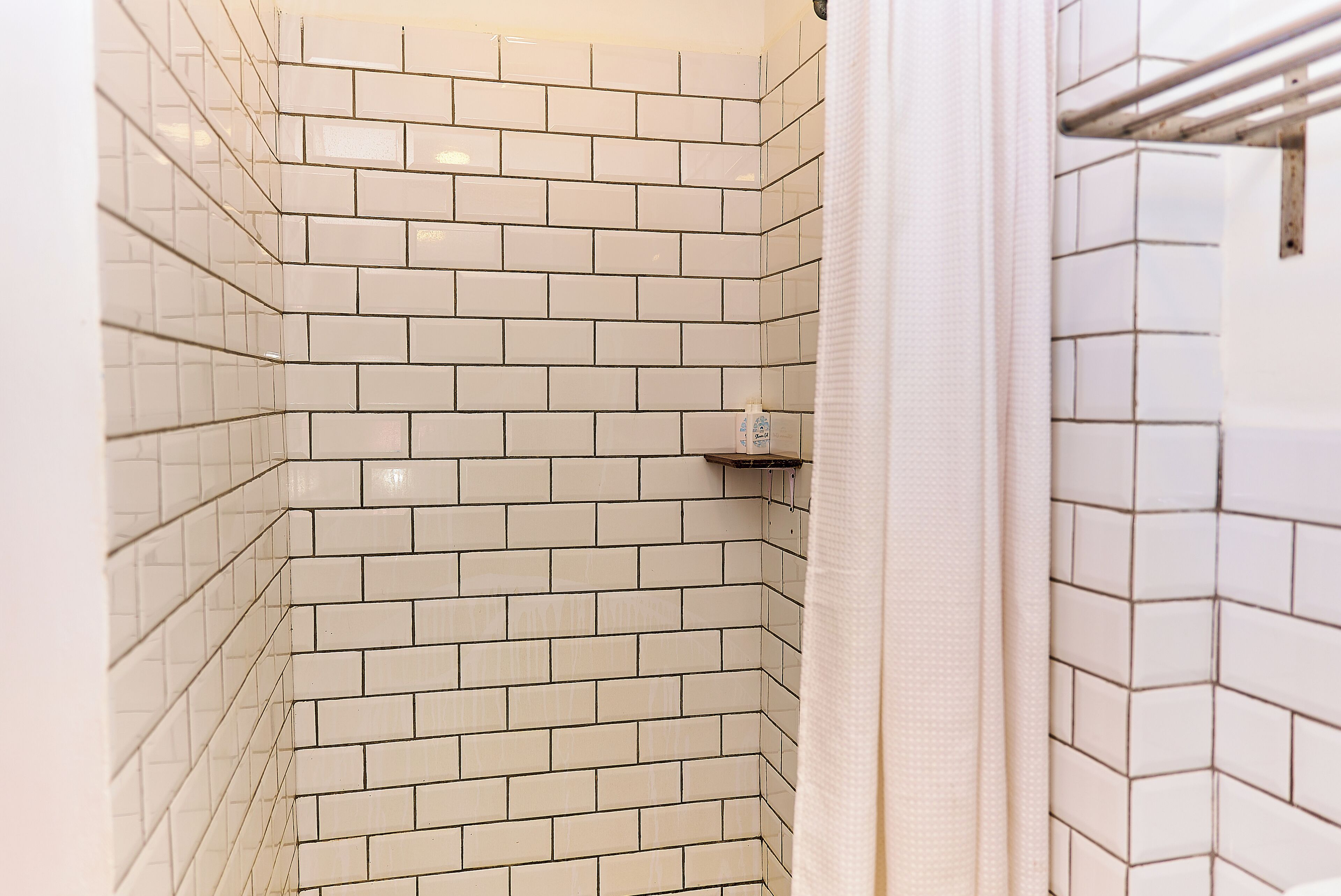 Un baño con azulejos blancos tipo metro, un perchero y un estante pequeño.