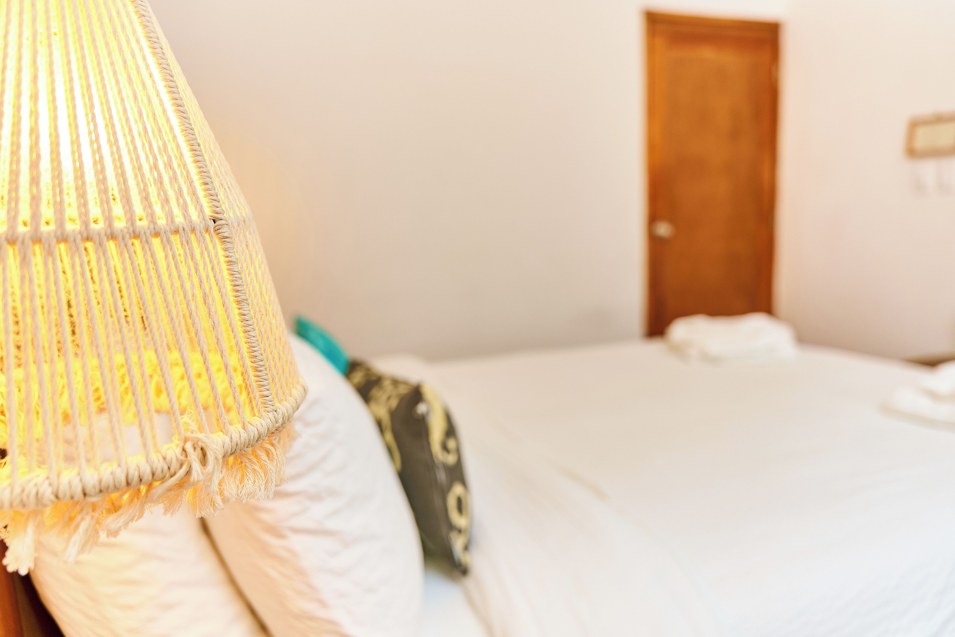 A bed with white bedding and a hanging light fixture.