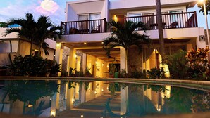 A modern hotel with a pool, balconies, and tropical plants. - Aaki Hotel (León)