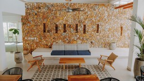 A modern interior with a stone wall, a wooden ceiling, and a seating area with a bench and chairs. - Apartamento en Baia Kristal (Cartagena)