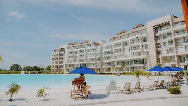 A resort with a pool, beach chairs, and umbrellas. - Apartamento en Baia Kristal (Cartagena)