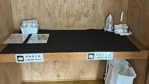Opbergruimte voor bagage met een houten vloer, een zwarte mat en een witte tas.