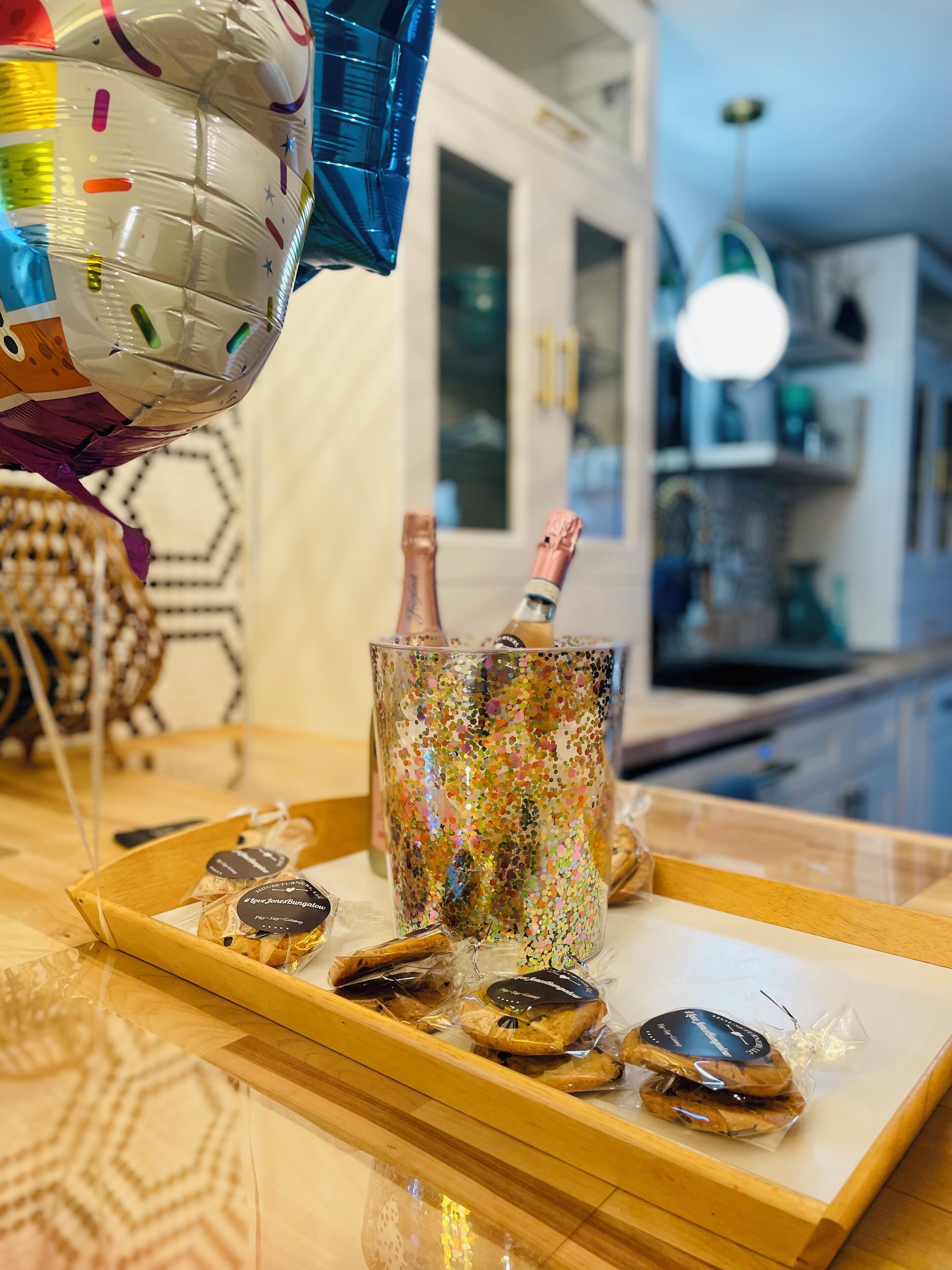 A tray with a glass mug, two bottles, and several cookies on a wooden table.