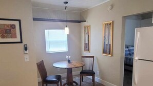 A kitchen with a dining table, chairs, a refrigerator, and a window.