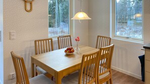 A dining area with a wooden table, six chairs, a vase with flowers, and a bowl of fruit. - 2 bedroom stunning home in Mönsterås (Mönsterås)