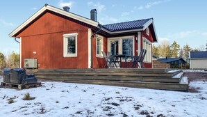 A red wooden house with a covered porch, a chimney, and a small outdoor seating area. - 2 bedroom stunning home in Mönsterås (Mönsterås)