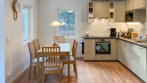 A compact kitchen with a dining table, chairs, a built-in oven, and a window with a view of trees. - 2 bedroom stunning home in Mönsterås (Mönsterås)