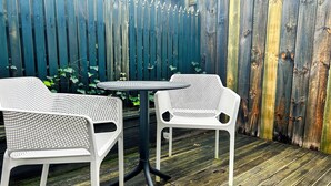 A small outdoor patio area with a round table and two white chairs. - Midway Motel Rotorua (Rotorua)