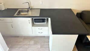 A compact kitchen with a sink, a microwave, and a countertop. - Midway Motel Rotorua (Rotorua)