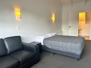 A bedroom with a bed, a sofa, and two wall-mounted lights.