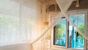 A bedroom with a canopy bed, a window with a view of outdoor furniture, and a hanging light fixture. - Siloe Cove (San Andrés)