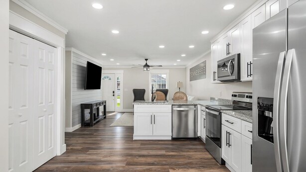 A modern kitchen with white cabinets, stainless steel appliances, and a wooden floor. - Charming 2-bedroom Duplex in quaint Algood area with WiFi, HVAC, Washer-Dryer (Cookeville)