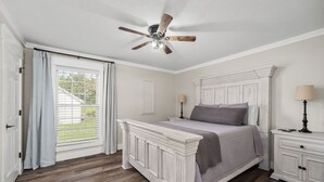 A bedroom with a white bed, a ceiling fan, a nightstand with a lamp, and a window with curtains. - Charming 2-bedroom Duplex in quaint Algood area with WiFi, HVAC, Washer-Dryer (Cookeville)
