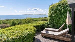 A deck with wicker lounge chairs and a table, overlooking a body of water and a green hedge. - 1 bedroom gorgeous home in Sønder Stenderup (Sønder Stenderup)