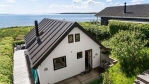 A white house with a steep roof, a small porch, and a view of a lake. - 1 bedroom gorgeous home in Sønder Stenderup (Sønder Stenderup)
