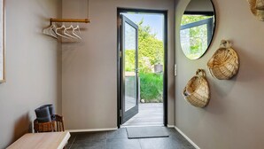 A hallway with a wooden door leading to an outdoor area, wicker baskets on the wall, and a small table with a chair. - 1 bedroom gorgeous home in Sønder Stenderup (Sønder Stenderup)