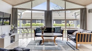 A spacious living area with a large window, a round table, and a sofa.