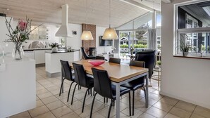 A modern kitchen with a central island, black chairs, and a wooden dining table.