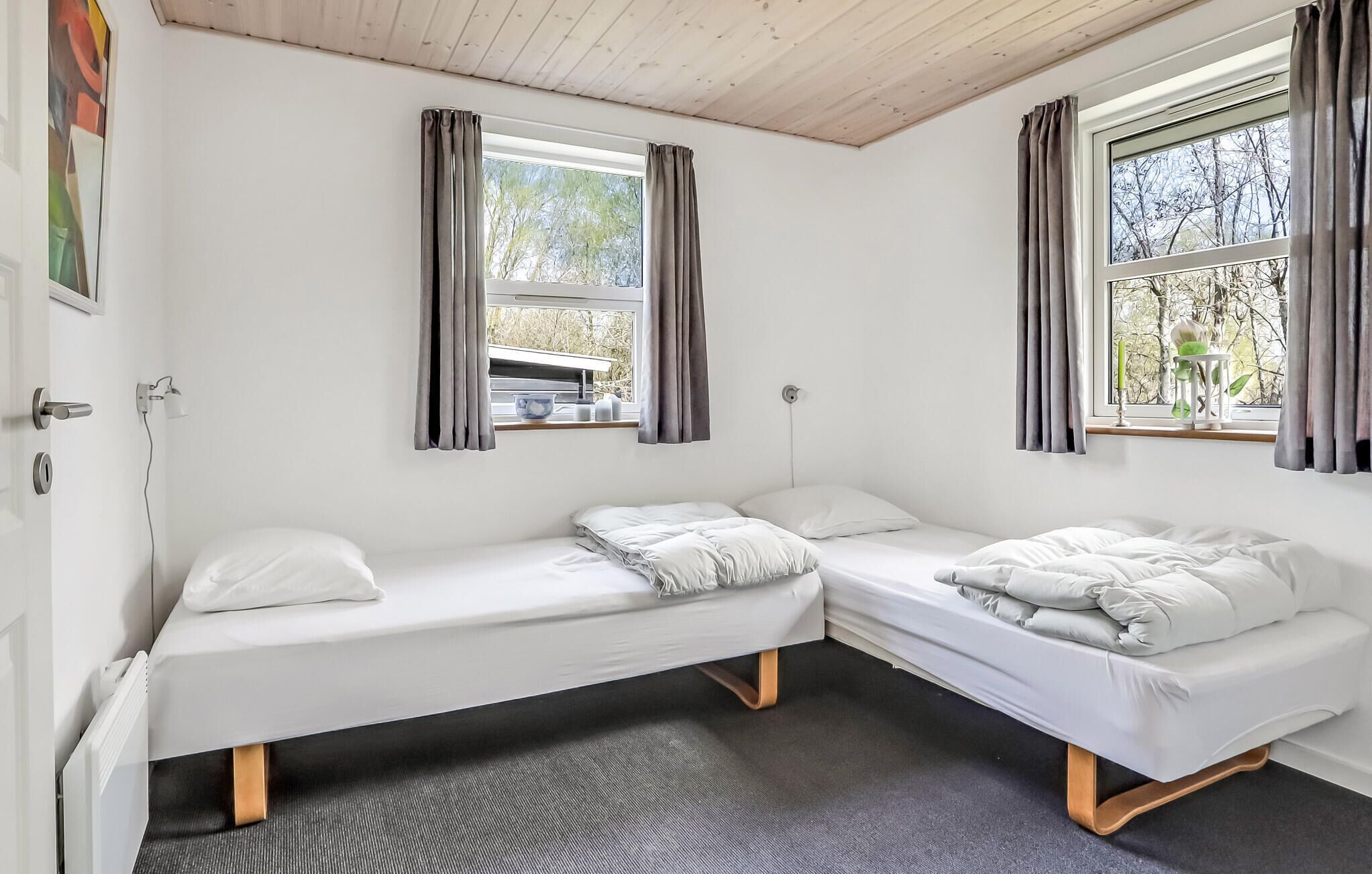 Ein Zimmer mit zwei Einzelbetten, einem Vorhangfenster, einem Heizkörper und einem kleinen Tisch mit einer Schale.