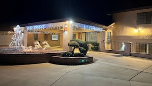 A building with a well-lit entrance, a small garden area with a decorative tree, and a sign with the number 2381. - Spacious Getaway: Patio, Pool, Hot Tub, Game Room (Apple Valley)