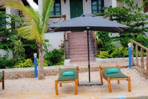 Relax in a serene garden setting with comfortable lounge chairs and a shaded area.