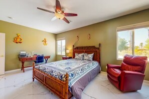 A bedroom with a wooden bed, a desk, a red chair, and a ceiling fan. - Desert Paradise Enjoy Private Pool & Spa with Game-room, Gym, Bikes&Scooters (Indio)