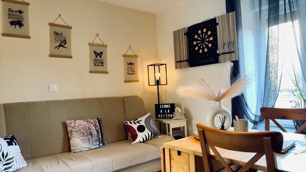 Ein gemütliches Wohnzimmer mit einer Couch, einem Esstisch und einer Dartscheibe.