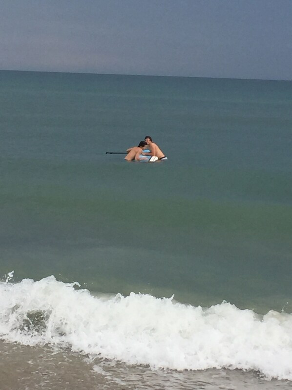 A person lying on a surfboard in the ocean.