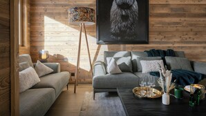 Ein gemütliches Wohnzimmer mit Holzboden, grauem Sofa, Couchtisch und einem gerahmten Lammel-Kunstwerk.