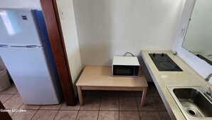 A compact kitchen with a refrigerator, a microwave on a small table, and a sink with a faucet. - Gulfway Motel By OYO Near Airport I 37 (Corpus Christi)