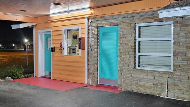 A building with a Coca-Cola vending machine, a garage door, and a small entrance with a red mat. - Gulfway Motel By OYO Near Airport I 37 (Corpus Christi)