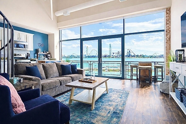 Spacious and stylish living room featuring a spiral staircase, open kitchen layout, and floor-to-ceiling windows that flood the space with natural light.