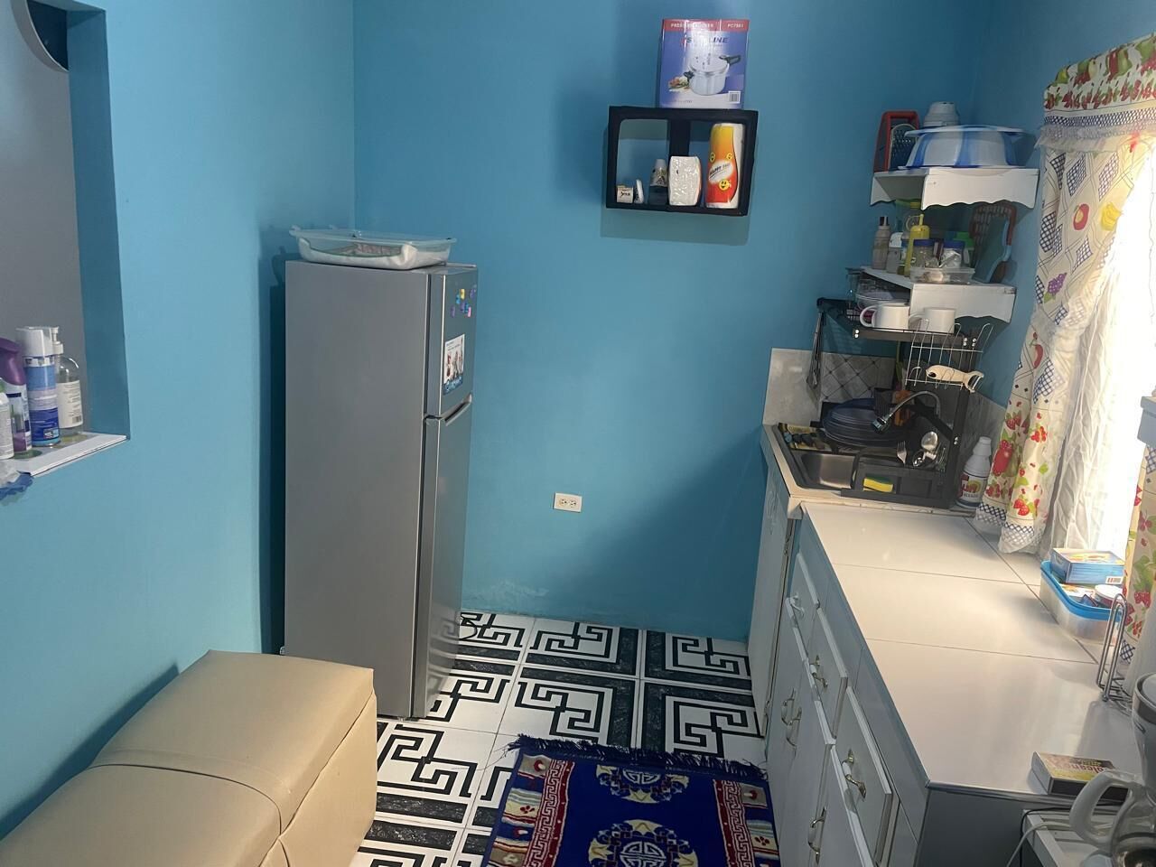 A compact kitchen with a refrigerator, a sink, and a countertop with various items.
