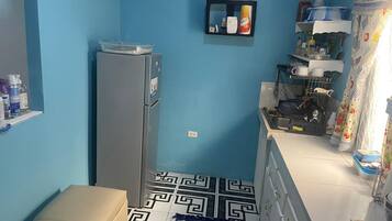 A compact kitchen with a refrigerator, a sink, and a countertop with various items.