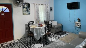 Uma sala de jantar com uma mesa, cadeiras e um ventilador de teto.