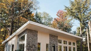 A modern house with a stone facade, large windows, and a covered porch area. - Nature & Confort: 3-bedroom cottage near Tremblant (Mont-Tremblant)