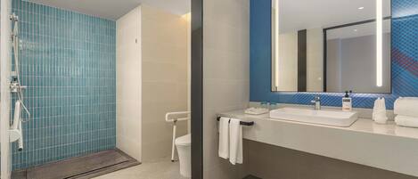 Une salle de bain moderne avec une douche à parois de verre, des toilettes, un lavabo avec un miroir et un porte-serviettes.