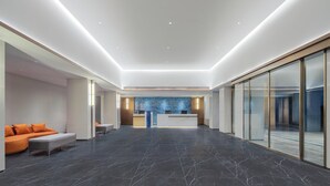 A modern hotel lobby with a reception desk, seating area, and a patterned wall. - Holiday Inn Express Longyan Liancheng by IHG (Longyan)