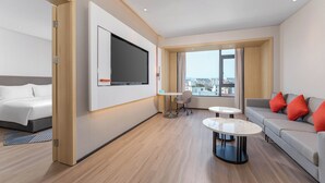 A modern hotel room with a bed, a sofa, a TV, and a city view. - Holiday Inn Express Longyan Liancheng by IHG (Longyan)