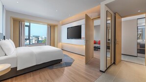 A modern hotel room with a large bed, a TV mounted on the wall, and a view of the cityscape through large windows. - Holiday Inn Express Longyan Liancheng by IHG (Longyan)