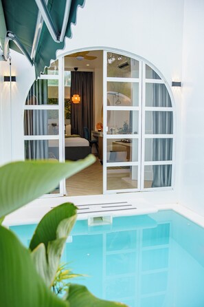 A hotel room with a glass door leading to a bedroom, a pool, and a view of the room's interior. - Amanzohi Siargao (General Luna)