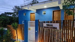 A building with a blue exterior, a wooden gate, and a sign that reads "Villa Margarita."